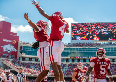 Two razorback football players chest bump.